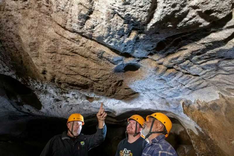 Mal and Dylan Siely examine finger grooves at Waribruk with GunaiKurnai Elder Uncle Russell Mullett. Photo by Jess Shapiro, courtesy of GunaiKurnai Land and Waters Aboriginal Corporation