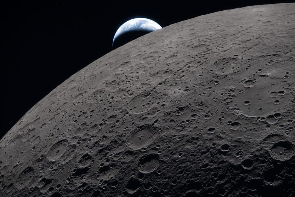 The lunar surface fills the frame in sharp detail, as seen during the Artemis II lunar flyby, while a distant Earth sets in the background. Constant bombardment by meteoroids and bits of asteroids has created a mottled, cratered surface covered by a fine dust called "regolith". Credit: NASA
