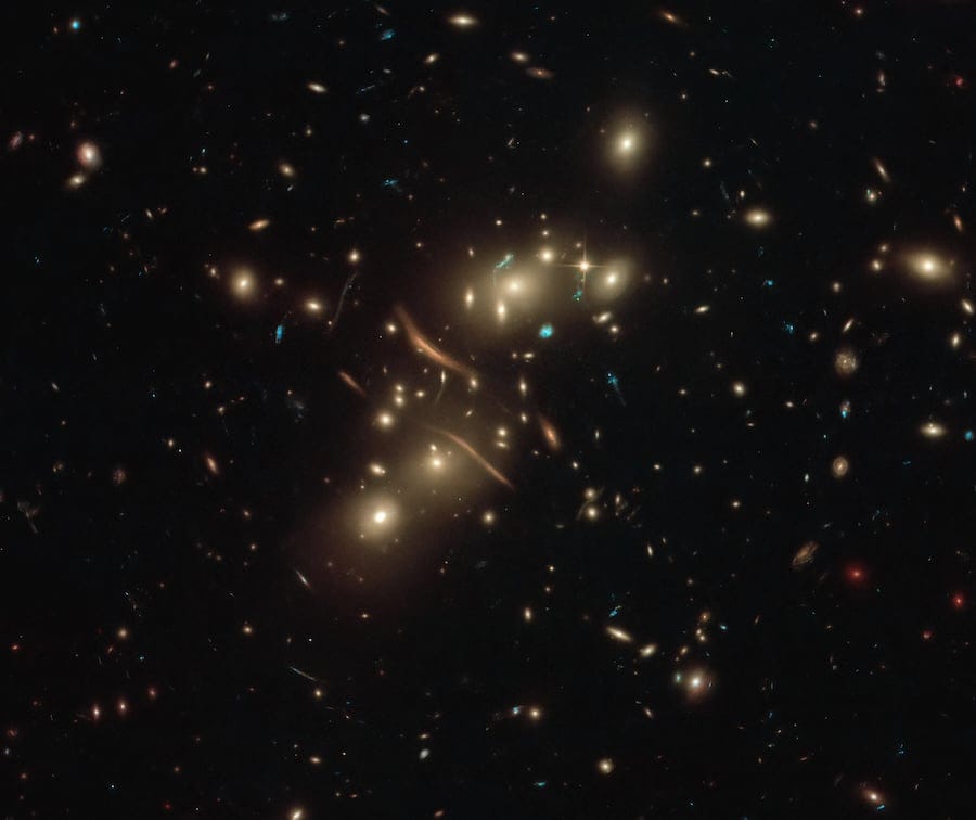 A foreground galaxy's gravity warps and magnifies the light of a quasar behind it, producing multiple distorted copies of a single object (Credit : NASA, ESA)