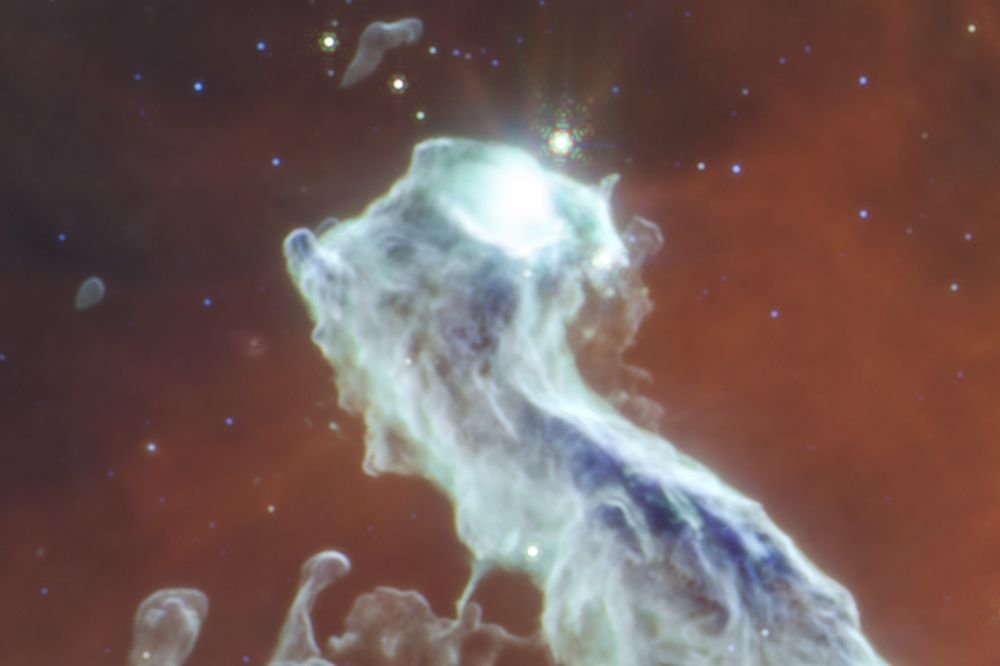 In this zoom-in of the MIR image, the edges are softened, and so are the colours. The star that makes they eye blends in with the gas in gradients of white. Globules below the head look like they're reaching for the head, rather than being blown back by stellar wind and radiation. The blackness of space is visible in the upper right, and a little in the upper left. Image Credit: NASA, ESA, CSA, STScI. Image Processing: J. Depasquale (STScI).